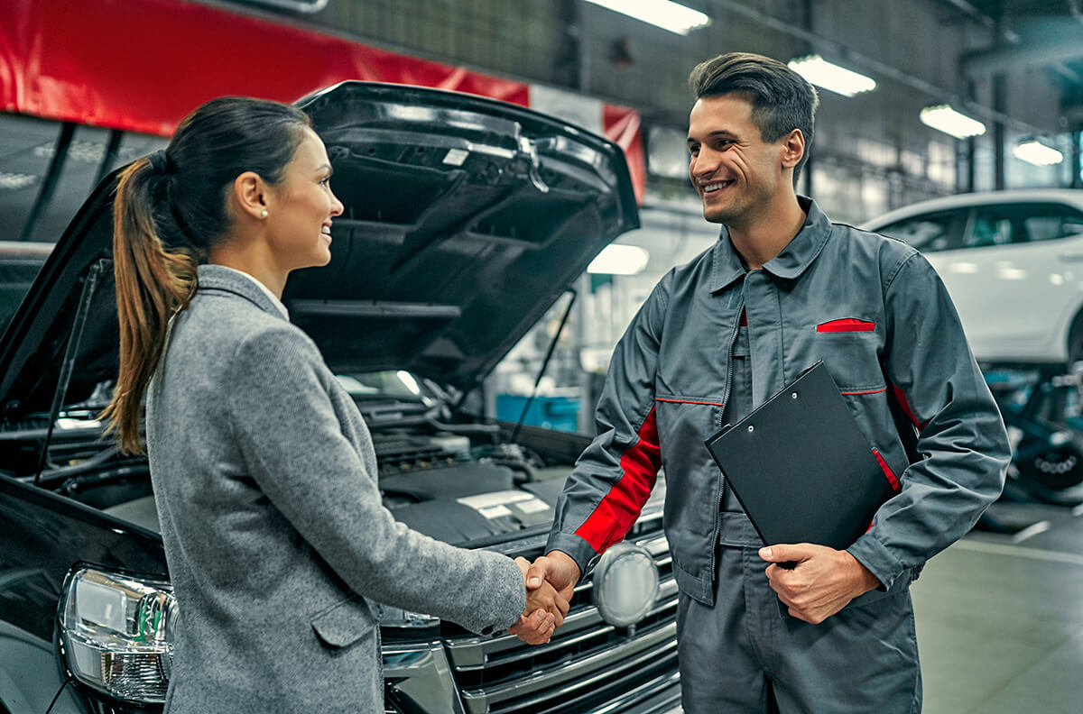 businesswoman and auto service mechanic shaking hands