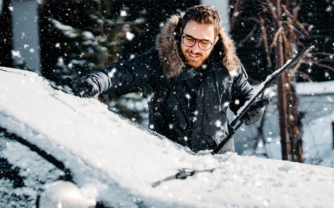 man cleaning snow off his car