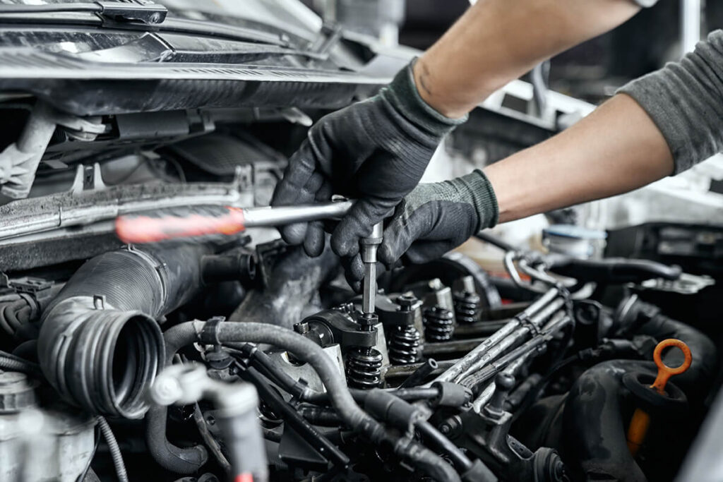 man's hands using wrench to remove spark plugs